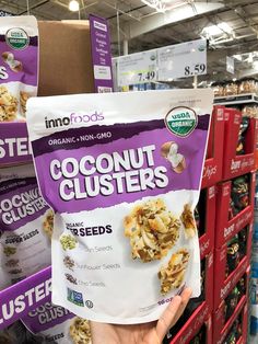 someone holding up a bag of coconut clusters in front of some other packages for sale