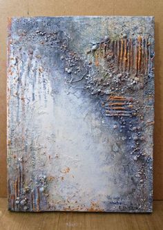 an abstract painting is displayed on a wooden surface with brown and blue colors, including rusted metal bars