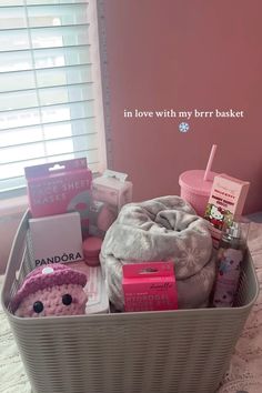 a basket filled with lots of different items on top of a bed next to a window