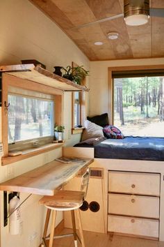 a room with a bed, desk and shelves on the wall next to a window