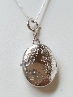 This Sterling Silver Locket is hand assembled onto a 16" 925 box chain. The locket has a beautiful floral pattern with 2 clear rhinestones above probably to indicate which way to wear. It is oval shaped hinged locket. On the inside hallmark: "Toni 925 China" . This item is new but hand assembled.  Locket measures: 1" L X 5/8" W Box Chain measures: 16" Material: Sterling Silver Locket and Chain Come in a gift box with tracking FREE SHIPPING Silver Oval Locket Necklace Nickel-free, Silver Oval Locket Necklace Nickel Free, Nickel-free Silver Oval Locket Necklace, Silver Flower Pendant Locket Jewelry, Silver Oval Locket Necklace With Adjustable Chain, Silver Jewelry With Flower Pendant Locket, Oval Silver Chain Jewelry, Elegant Pendant Locket Necklace Stamped 925, Sterling Silver Oval Locket Necklace, Nickel-free