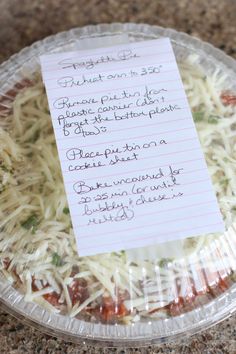 a pizza covered in cheese and sauce with a note pinned to it on a plastic plate