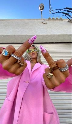 a woman with her hands in the air and two fingers out, wearing pink clothing