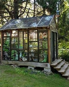 a small greenhouse in the middle of a grassy area with steps leading up to it