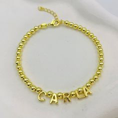 Make a stylish statement with the Luxe Beaded Name Bracelet. Embellished with shiny gold beads and refined letter charms, this bracelet can be customized with your name or a unique word, making it a timeless addition to any collection. Latina Culture, Unique Words, Custom Earrings, Name Bracelet, Letter Charms, Custom Bracelets, Custom Necklace, Gold Beads, Custom Rings