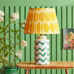 a lamp sitting on top of a wooden table next to a vase with flowers in it