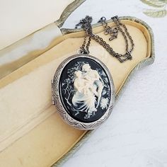 Classical style Victorian inspired large cameo locket necklace in black and cream. The detailed cameo has a black background, and is set on a large opening locket in gunmetal or antiqued bronze plated on a matching chain. The locket will hold two photos (approx the same size as the cameo), or any small precious object.  The locket measures just under 2 inches (50mm) from top to bottom, and the matching chain is has a lobster clasp. The chain length can be altered at no extra cost. Choose gunmetal plated or antiqued bronze plated. This necklace comes in a gift box. Black Engraved Necklace For Wedding, Vintage Black Locket Necklace, Black Medallion Locket Necklace As A Gift, Vintage Black Cameo Necklace, Black Cameo Jewelry For Collectors, Black Cameo Necklace In Vintage Style, Antique Cameo Necklace Keepsake, Antique Cameo Necklace As Keepsake, Antique Cameo Necklace For Keepsake