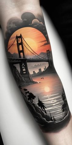 a man with a tattoo on his arm that has a sunset and a bridge in the background