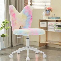 a colorful office chair sitting on top of a wooden floor in front of a window