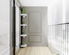 an empty room with white walls and wooden flooring, along with plants on shelves