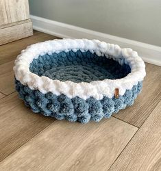 a blue and white crocheted dog bed on the floor