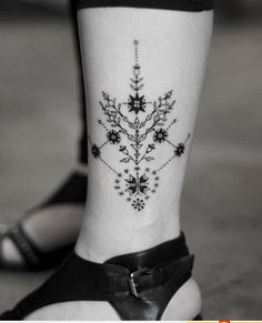 a black and white photo of a woman's foot with a flower tattoo on it