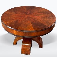 a round wooden table sitting on top of a white floor