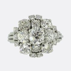 Here we have a truly beautiful old cut diamond ring dating back to the mid 20th century. The ring features a raised central old cut diamond that weighs approximately 1.0 carat and is surrounded by 18 slightly smaller old cuts. In total it plays host to an impressive 4.50 carats of diamonds that are well matched for colour and clarity and give off a spectacular sparkle. The ring is perfect for evening wear and would draw attention on any occasion. It is crafted in platinum and the shoulders are r Victorian Cluster Ring With Brilliant Cut In Diamond White, Victorian Diamond Ring With Vvs Clarity, Antique White Cluster Ring With Brilliant Cut, Victorian Diamond White Brilliant Cut Diamond Ring, Victorian Style Diamond White Diamond Ring With Brilliant Cut, Victorian Style Brilliant Cut Diamond White Diamond Ring, Victorian White Diamond Ring In Platinum, Victorian Style Brilliant Cut Diamond White Ring, Antique Cluster Diamond Ring With Center Stone