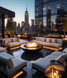 an outdoor fire pit surrounded by white couches and tables with lit candles on them