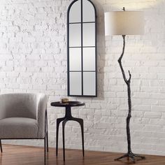 a room with a chair, table and mirror on the wall next to a lamp