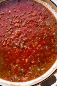 a large pot filled with lots of red sauce on top of a stove burner