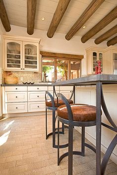 a kitchen with two stools and a bar in the middle, next to an oven