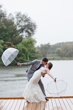 a bride and groom kissing on a dock with an umbrella