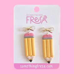 some pink and yellow pencils are hanging from the back of a pair of earrings