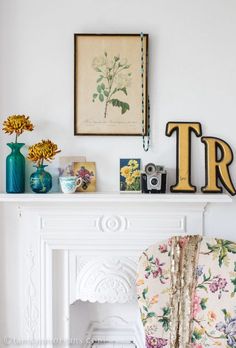 there is a chair and some flowers on the mantle