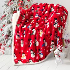 a red blanket with snowmen on it next to a christmas tree