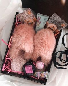 a pink teddy bear laying in a box with its eyes closed and other items around it