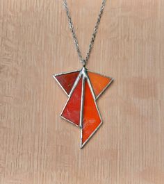 an orange and red necklace on a wooden surface with a chain hanging from the neck