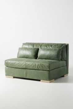 a green couch with two pillows on it's back and one arm folded up