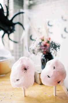 two cotton candy lollipops with eyes drawn on them sitting on a table