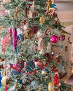 a christmas tree with ornaments hanging from it's branches and decorations on the top