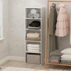 a white shelf filled with folded towels next to a wall mounted rack full of folded clothes