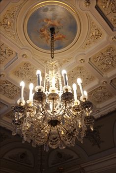 a chandelier hanging from the ceiling in a room with ornate ceilings and paintings