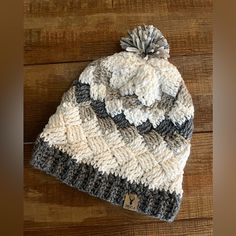 a knitted hat with a pom - pom sitting on top of a wooden table