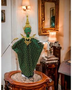 a green statue sitting on top of a wooden table next to a mirror and lamp