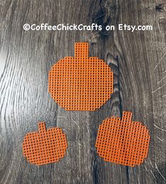 three orange pumpkin coasters sitting on top of a wooden table