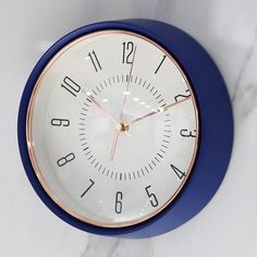 a blue and white clock sitting on top of a marble counter next to a wall