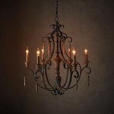 a chandelier hanging from a ceiling with candles lit up in the dark room