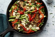 a skillet filled with meat, vegetables and feta cheese on a white table