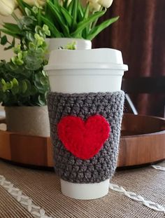 a coffee cup with a crocheted heart on it