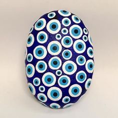 an egg with blue and white circles painted on it's side, sitting in front of a gray background