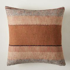 a brown and blue striped pillow sitting on top of a white wall