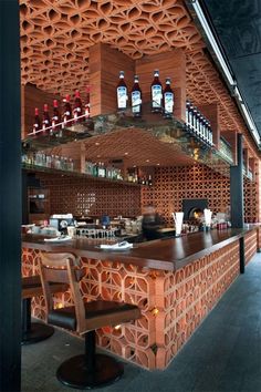 the interior of a restaurant with wooden tables and stools in front of shelves that have bottles on them