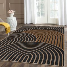 a black and tan area rug in front of a white vase with flowers on it