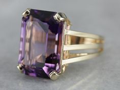 "This amethyst cocktail ring features an outstanding amethyst straight from the source, we purchased it on one of our buying trips to Brazil. The play of light is outstanding and the depth of color is exquisitely filled with flashes of violet and raspberry! A perfect piece to celebrate any occasion from anniversary to birthday and everything in between! Metal: 14K Yellow Gold Gem: Amethyst 10.00 Carats (approximately) Gem Measurements: 17.9 x 13 mm, Emerald Cut Ring Size: 6 Marks: \"14K JM\" Sta Amethyst Cocktail Ring, Emerald Cut Ring, Emerald Cut Rings, February Birthstone, February Birth Stone, Amethyst Ring, The Source, Cocktail Ring, Cocktail Rings