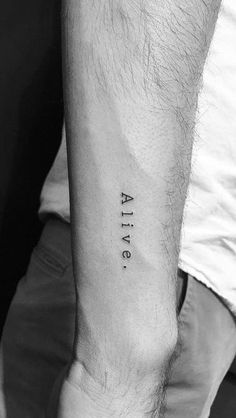 a man's arm with the word alive tattooed on his left forearm, in black ink