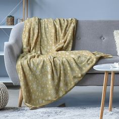 a couch with a blanket on top of it in front of a table and chair