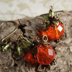 "A new twist to my original designthese adorable little pumpkins in spicy orange, faceted glass beads, dangle from a sparkly vine of tiny glass beads in peridot green. Still crowned in layers of antiqued brass leaves and curlycues vines these little pumpkins are perfect for that person wanting just a little bit more spice! Length from bottom loop of french earwire: 1.5\"(33mm) Prefer a different style of earwires? Non pierced clips as well as leverbacks are also available for no extra charge. Pl Vine Earrings, Pumpkin Vine, Peridot Green, Pumpkin Earrings, Orange Pumpkin, Pretty Box, Pumpkin Orange, Faceted Glass, Pumpkins