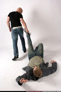 two men in jeans and black shirts standing over another man laying on the ground