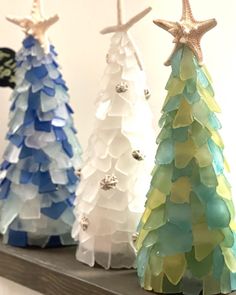 three different colored christmas trees sitting on top of a shelf